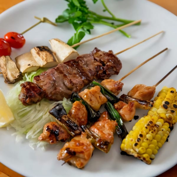 Grilled skewers of chicken, beef, mushrooms, cherry tomatoes, and corn on a white plate.