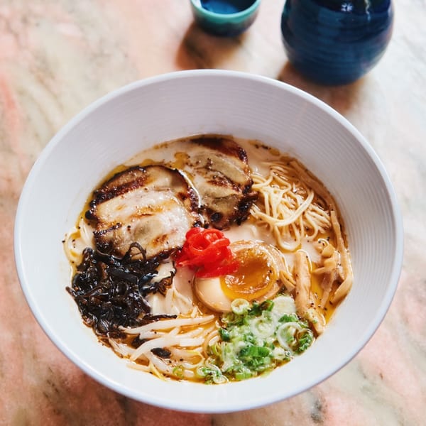 Close-up of a bowl of Sapps Nyc ramen with pork, egg, noodles, and various toppings.
