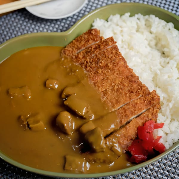 Japanese chicken katsu curry with white rice and red pickled ginger in a green heart-shaped bowl.