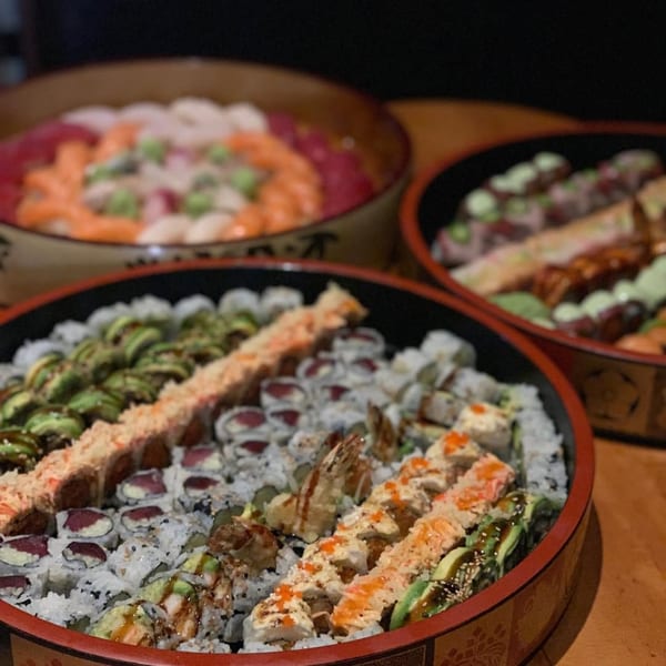 Three large platters of various Sapps Nyc Japanese sushi rolls and sashimi are displayed.