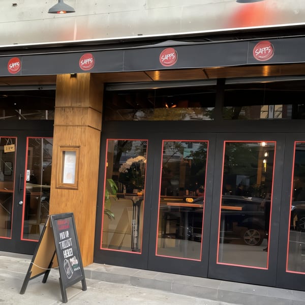 Exterior of Sapps Nyc, a Japanese restaurant, with a black awning, glass doors, and a sandwich board.
