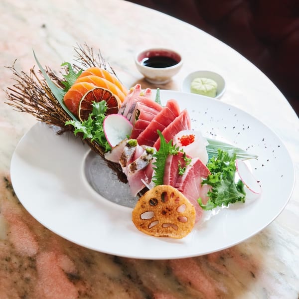 Assorted sashimi platter with salmon, tuna, and other fish, garnished with citrus and greens.