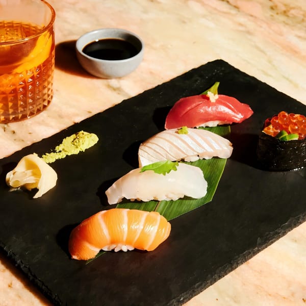 Assorted Sapps NYC sushi and nigiri, with soy sauce, wasabi, ginger, and a cocktail.